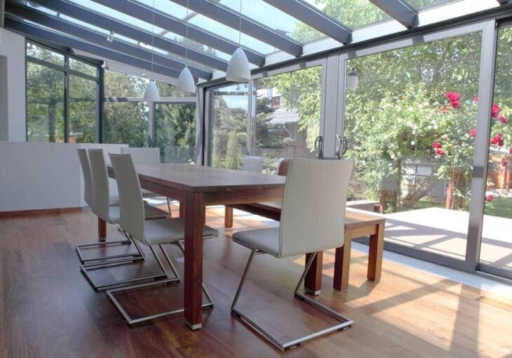 Modern glass conservatory dining area with no blinds installed, showing potential for conservatory window blinds