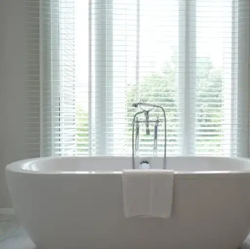 White venetian blinds for bathroom window above bathtub