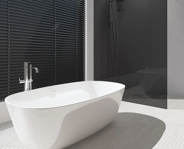 Gloss black bathroom Venetian blinds behind a modern freestanding white bath.