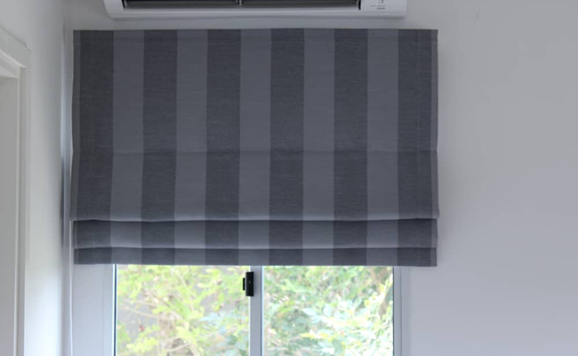 Grey striped bathroom Roman blind fully drawn over a small window, adding privacy and style.