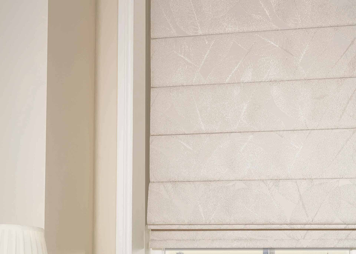 Pearl-coloured Roman blind with subtle leaf pattern, fully lowered in a bright bathroom window.