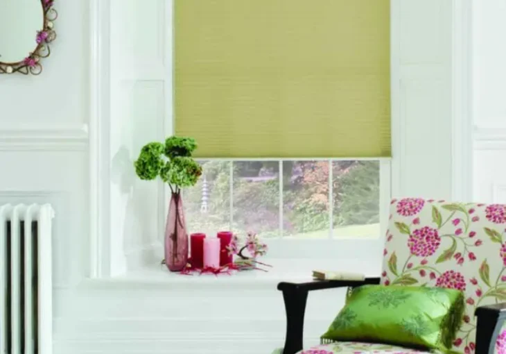 Pale green roller blind in a bright living room with floral chair and decorative accents